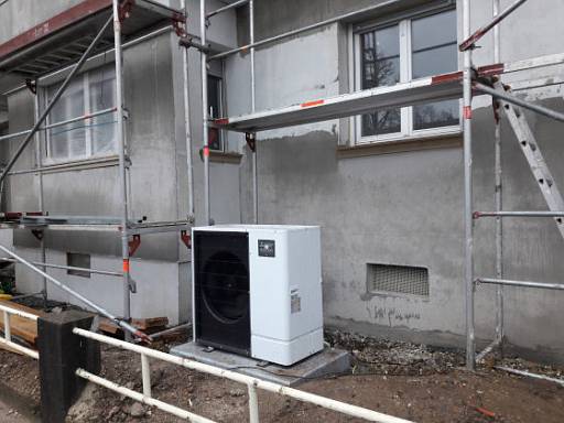 Luftwärmepumpe vor einem Altbau mit Baugerüst © energie-fachberater.de